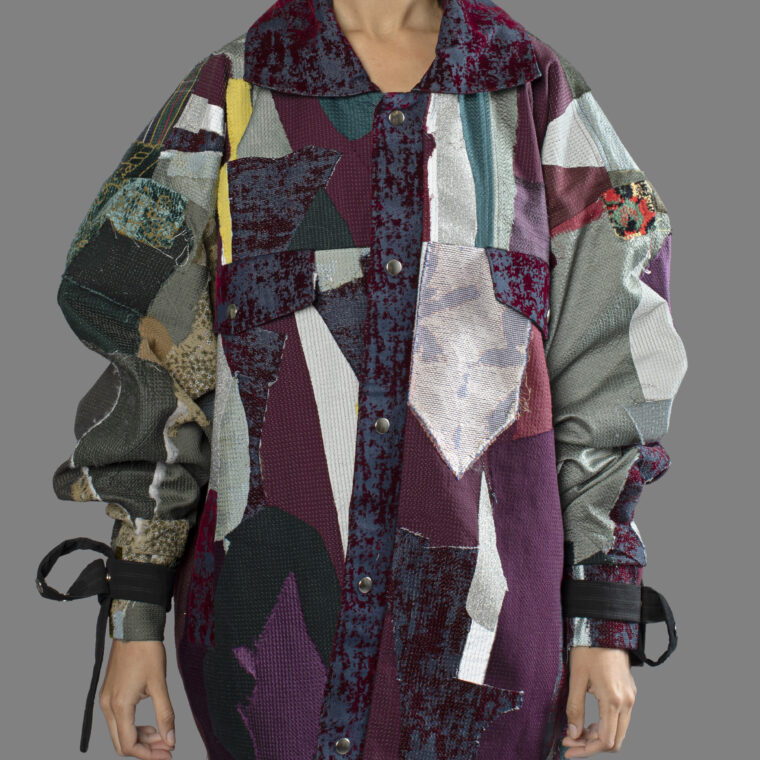 This is an image of a scrap coat jacket from the brand MiJA. It consists of mix of dark purple and green fabrics. There are also few reflective textile pieces in the mix.